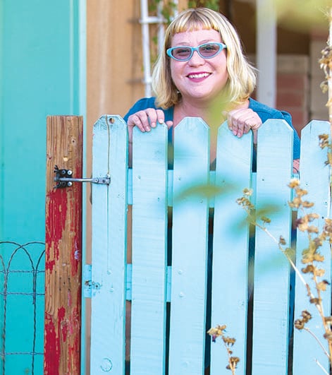 A woman stands behind a bright green fence