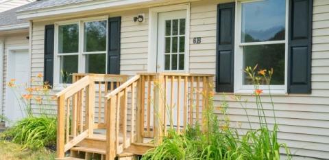 A closeup of a home with a front porch and shutters.